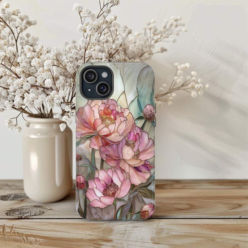 May include: A phone case with a stained glass design featuring pink and white peonies. The case has a clear back and a black camera cutout.