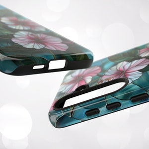 May include: Two phone cases with a floral design. The cases are black with a clear back that shows a blue and green background with pink flowers.