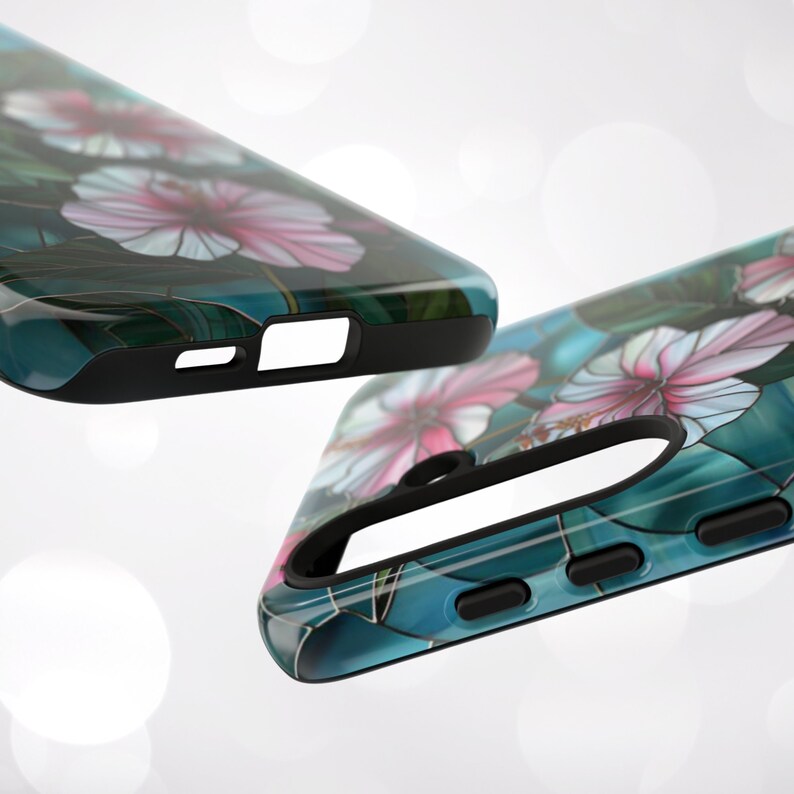 May include: Two phone cases with a floral design. The cases are black with a clear back that shows a blue and green background with pink flowers.