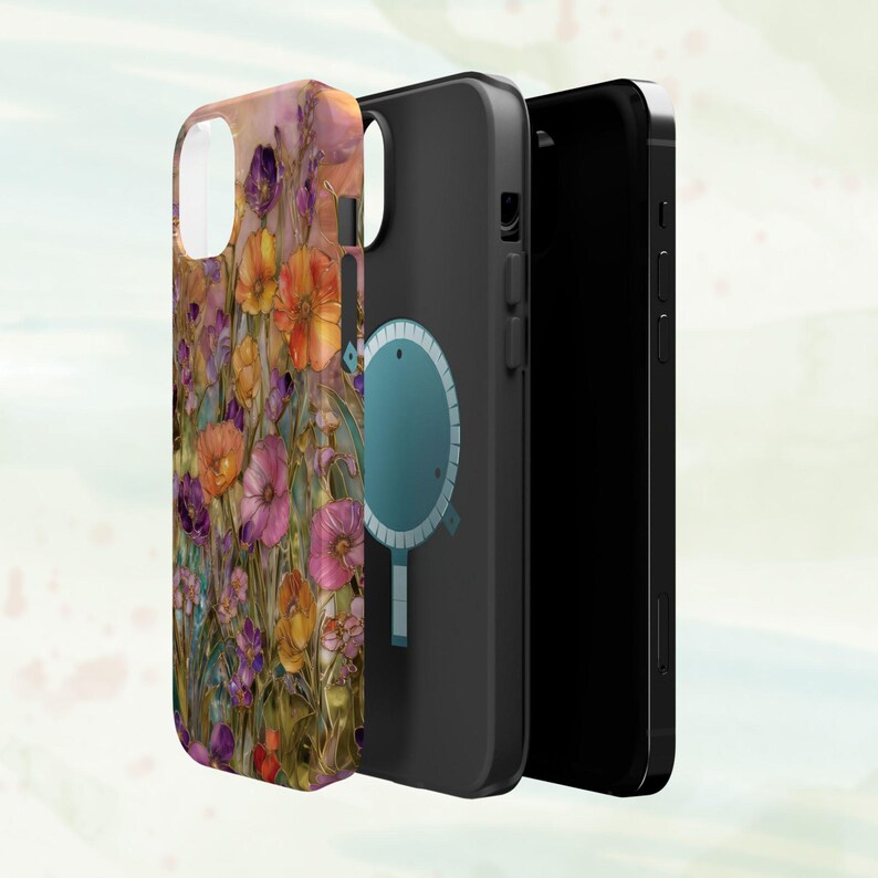 Op de afbeelding: Een telefoonhoesje met een bloemenontwerp in tinten oranje, paars en roze. De hoes wordt getoond naast een zwarte telefoon en een zwarte telefoonhoes met een blauwe cirkel.