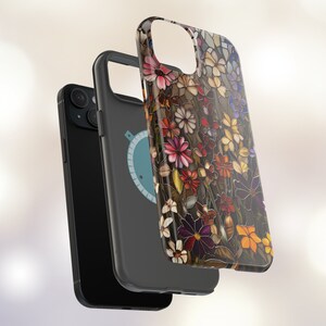 May include: A black phone case with a floral design. The case features a colourful stained glass pattern with flowers in shades of red, pink, purple, and yellow. The case is designed to fit a smartphone with a camera bump.