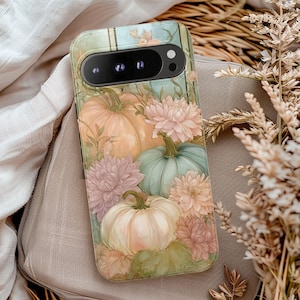 May include: A phone case featuring a watercolor design of pumpkins and flowers in shades of peach, green, and pink. The case has a glossy finish and a camera cutout. The design includes pumpkins, dahlias, and foliage, creating a fall or autumn theme.