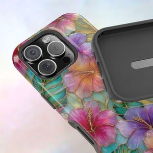May include: A protective phone case featuring a vibrant floral pattern with pink, purple, and orange hibiscus flowers accented by teal tropical leaves and thin gold outlines. The case has a black interior lining and a triple camera cutout.