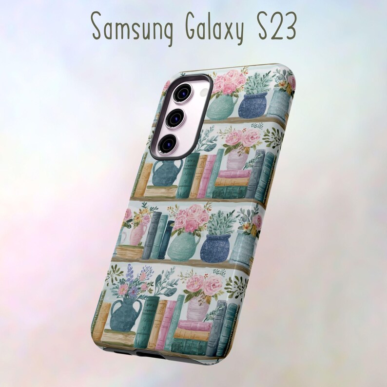 Peut inclure: Coque de t&eacute;l&eacute;phone Samsung Galaxy S23 avec un motif aquarelle de biblioth&egrave;ques, de vases de fleurs et de piles de livres. Le bo&icirc;tier a un module cam&eacute;ra blanc et noir. Le texte "Samsung Galaxy S23" est en haut.