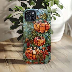 May include: A stained glass style phone case with a design of orange pumpkins on a vine with green leaves.
