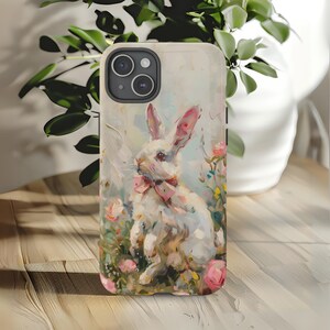 K&ouml;nnte beinhalten: Ein wei&szlig;es Kaninchen mit einer rosa Schleife sitzt in einem Feld mit rosa und wei&szlig;en Blumen. Das Kaninchen ist in einem realistischen Stil mit einem weichen, vertr&auml;umten Hintergrund gemalt.