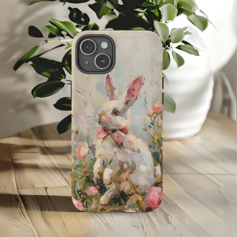 K&ouml;nnte beinhalten: Ein wei&szlig;es Kaninchen mit einer rosa Schleife sitzt in einem Feld mit rosa und wei&szlig;en Blumen. Das Kaninchen ist in einem realistischen Stil mit einem weichen, vertr&auml;umten Hintergrund gemalt.