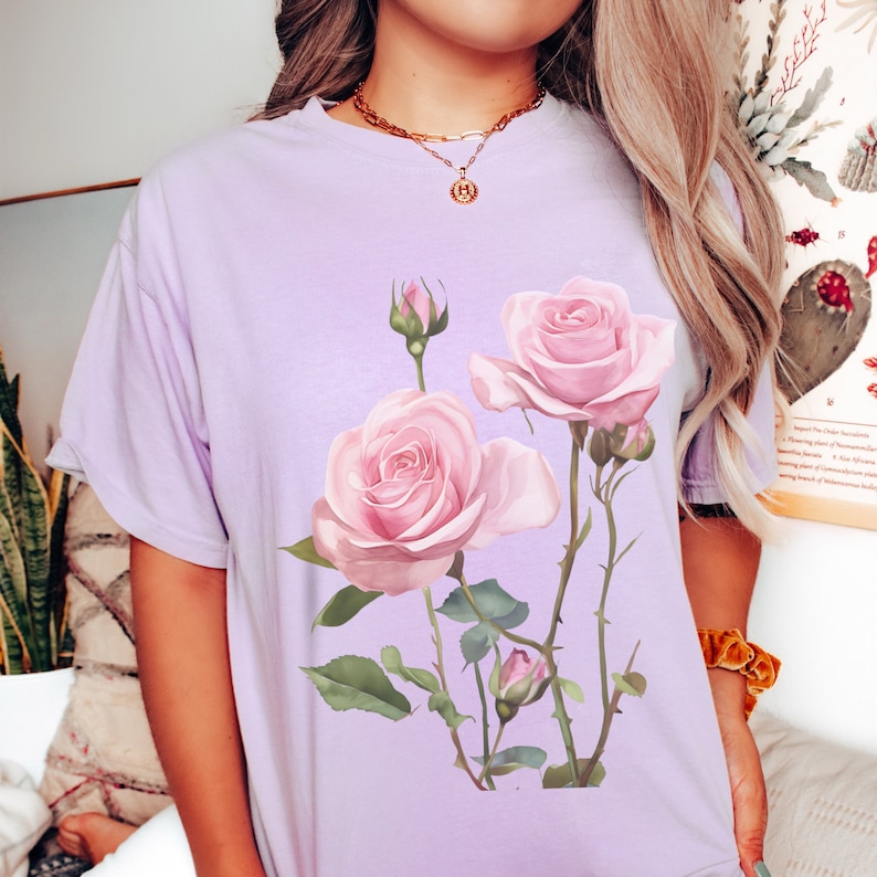 May include: A lavender t-shirt with a floral design featuring pink roses and green leaves.