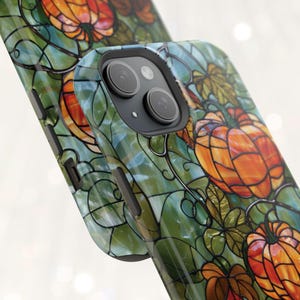 May include: A phone case with a stained glass design featuring pumpkins and vines in shades of orange, green, and brown.