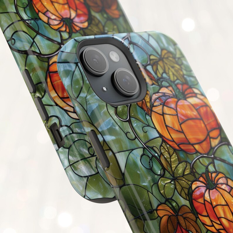 May include: A phone case with a stained glass design featuring pumpkins and vines in shades of orange, green, and brown.