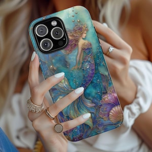 May include: A phone case featuring a mermaid design in shades of blue, purple, and gold. The artwork depicts a mermaid with flowing hair and a scaled tail, surrounded by bubbles and aquatic elements. The case has a glossy finish.