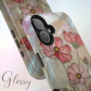 May include: A pearlescent phone case featuring a floral design with pink cosmos flowers and green stems. The case has a glossy finish and the word "Glossy" is written on the bottom left corner.