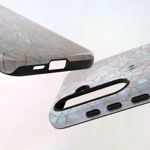 May include: Two phone cases with a marble-like design. The cases are black with a white and blue marble pattern. The cases are shown from different angles.