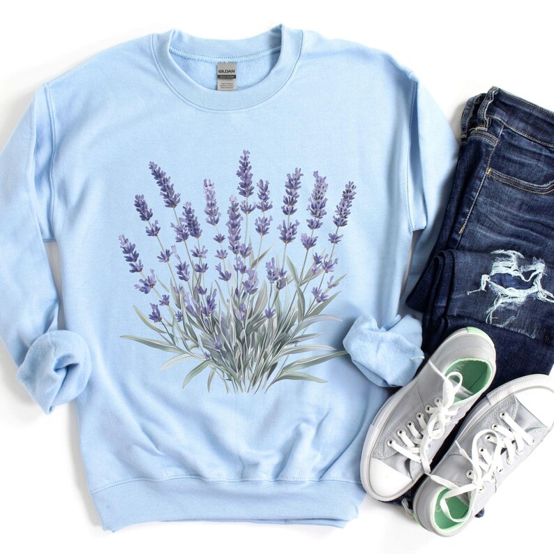 Op de afbeelding: Een lichtblauw sweatshirt met een bloemenprint van lavendelbloemen. Het sweatshirt heeft een ronde hals en lange mouwen.