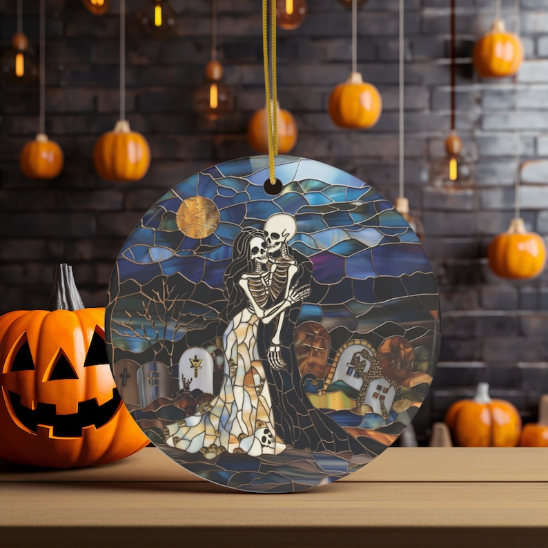 May include: A round, stained glass ornament featuring a skeletal couple embracing in a graveyard setting. The background is a dark blue sky with a full moon and stars. The ornament is perfect for Halloween decor.