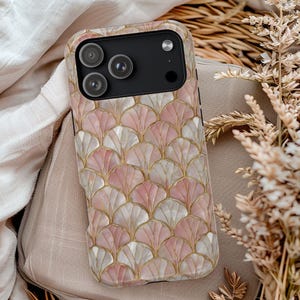 May include: A smartphone case with a pink, white, and gold fan-shaped pattern. The case has a black camera module with three lenses. The design is reminiscent of Art Deco style, with a pearlescent finish.