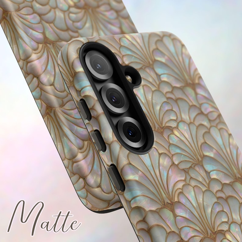 May include: A matte phone case with a pearlescent, fan-shaped design in shades of white, gold, and iridescent hues. The case features a triple-lens camera cutout and side buttons. The word "Matte" is printed in a cursive font.