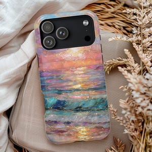 May include: A smartphone case featuring a colorful ocean sunset design. The case has a black camera module and a vibrant, artistic depiction of waves in shades of blue, pink, and gold.