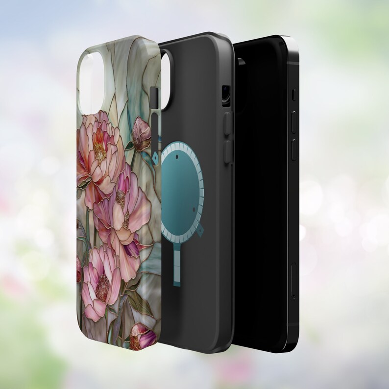 May include: A black phone case with a floral design. The case has a clear back and a black front with a circular cutout for a magnetic phone holder. The floral design features pink and white peonies on a green background.