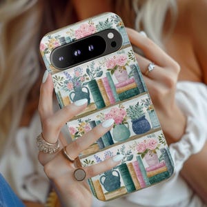 Peut inclure: Coque de t&eacute;l&eacute;phone &agrave; motif floral repr&eacute;sentant des &eacute;tag&egrave;res avec des livres, des vases et des fleurs roses, bleues, vertes et jaunes. L'&eacute;tui a une finition brillante et une d&eacute;coupe pour l'appareil photo.