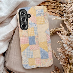 May include: A phone case with a patchwork design in pastel colors. The case features squares of blue, pink, yellow, and cream fabrics with floral and gingham patterns. The phone's camera lenses are visible on the upper left.