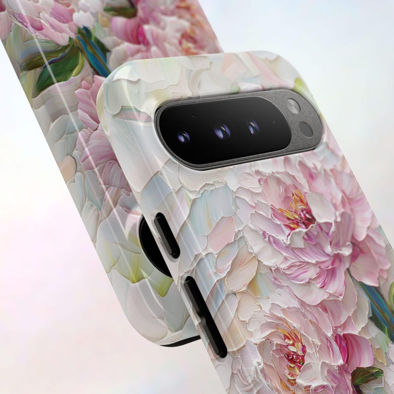 K&ouml;nnte beinhalten: Eine wei&szlig;e Handyh&uuml;lle mit einem Blumendesign mit rosa Pfingstrosen, die in einem strukturierten Stil gemalt sind. Die H&uuml;lle hat einen schwarzen Ausschnitt f&uuml;r das Kameraobjektiv.