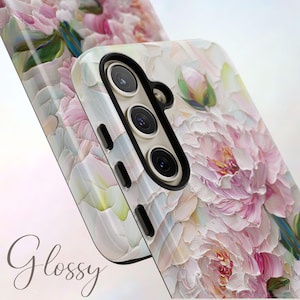 K&ouml;nnte beinhalten: Eine wei&szlig;e Handyh&uuml;lle mit einem Blumendesign aus rosa und wei&szlig;en Pfingstrosen. Die H&uuml;lle hat eine gl&auml;nzende Oberfl&auml;che und einen Kameraausschnitt mit drei Objektiven.