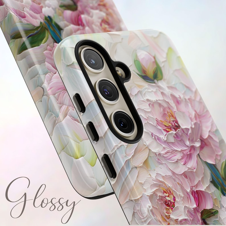 K&ouml;nnte beinhalten: Eine wei&szlig;e Handyh&uuml;lle mit einem Blumendesign aus rosa und wei&szlig;en Pfingstrosen. Die H&uuml;lle hat eine gl&auml;nzende Oberfl&auml;che und einen Kameraausschnitt mit drei Objektiven.