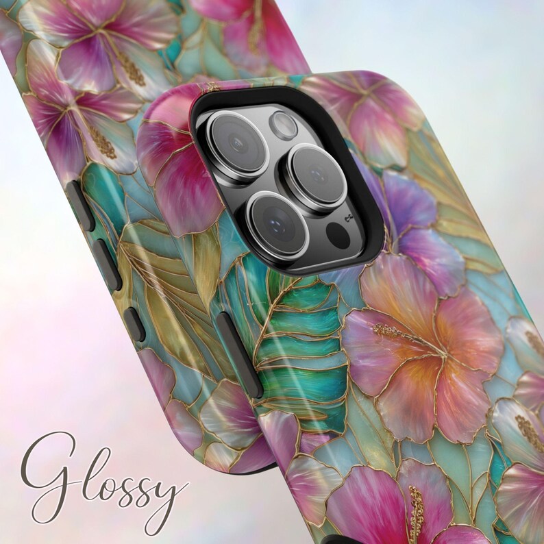 May include: A glossy phone case featuring a vibrant floral pattern with pink and orange hibiscus flowers, teal tropical leaves, and gold-toned outlines. The case has a black camera cutout frame and black side buttons for a smartphone device.