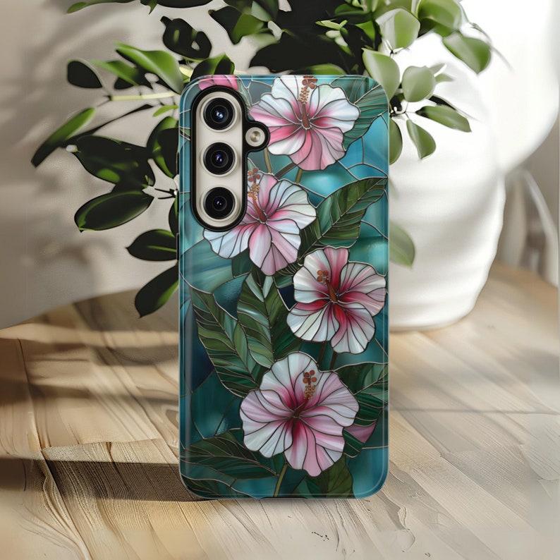 May include: A phone case with a stained glass design featuring pink and white hibiscus flowers on a teal background.