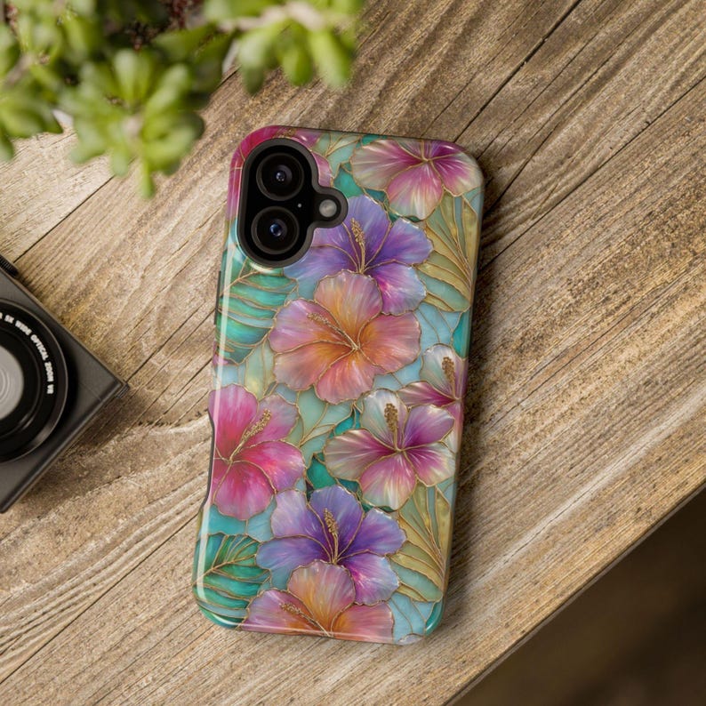 May include: A rectangular smartphone case featuring a vibrant floral pattern with hibiscus flowers in shades of pink, purple, and orange, accented by teal green leaves and gold-colored outlines, with a dual-lens camera cutout at the top left.