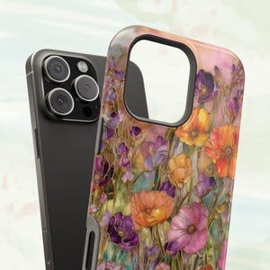 Op de afbeelding: Een smartphonehoesje met een bloemenpatroon met oranje, paarse en roze bloemen. De hoes heeft een glanzende afwerking en een zwarte rand. Een zwarte smartphone is ernaast te zien.
