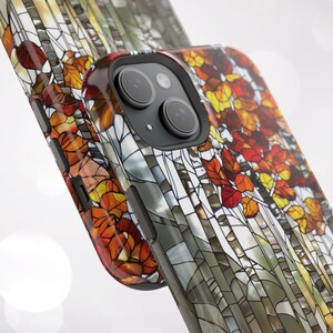 May include: A smartphone case featuring a stained-glass design with autumn leaves in shades of red, orange, and yellow. The case has a glossy finish and a black camera module.