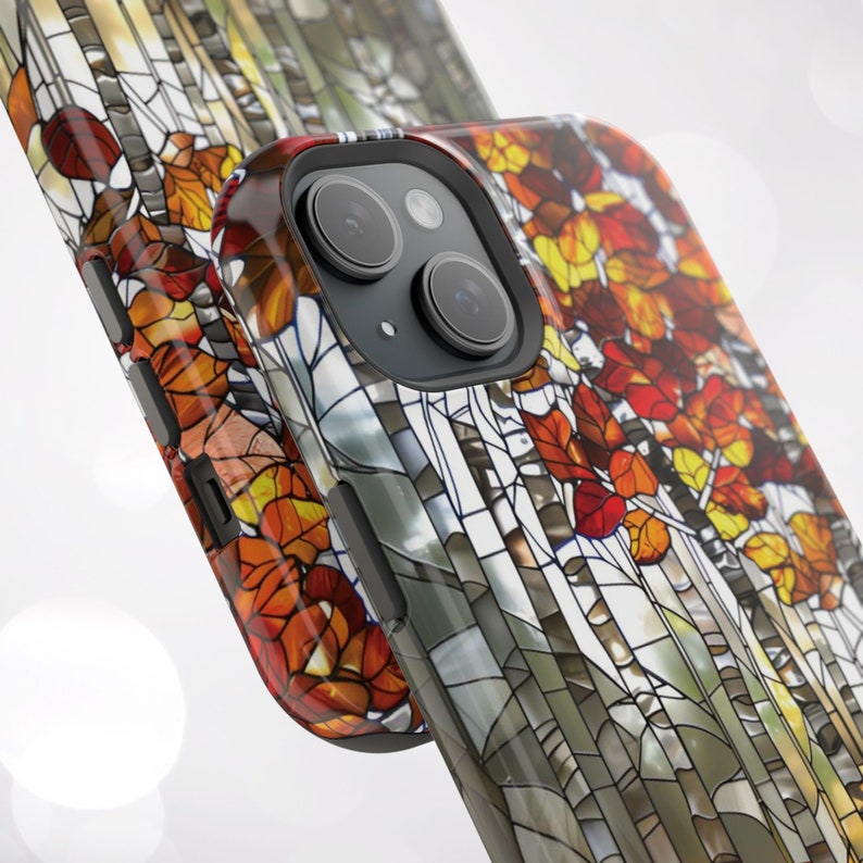 May include: A smartphone case featuring a stained-glass design with autumn leaves in shades of red, orange, and yellow. The case has a glossy finish and a black camera module.