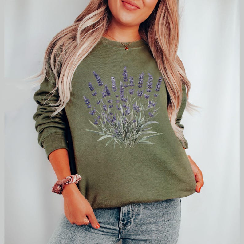 Op de afbeelding: Een groen sweatshirt met een lavendelbloemenprint. Het sweatshirt heeft lange mouwen en een ronde hals.