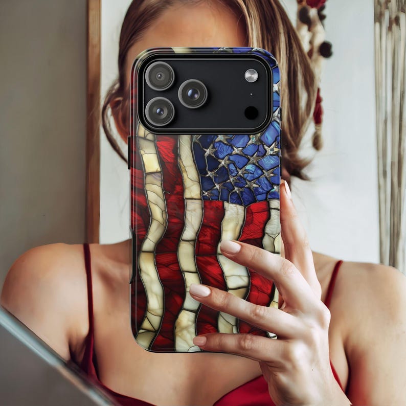 May include: A smartphone case featuring a stained-glass design of the American flag. The case has a black border and a glossy finish. The flag design incorporates red and white stripes with a blue field of stars.