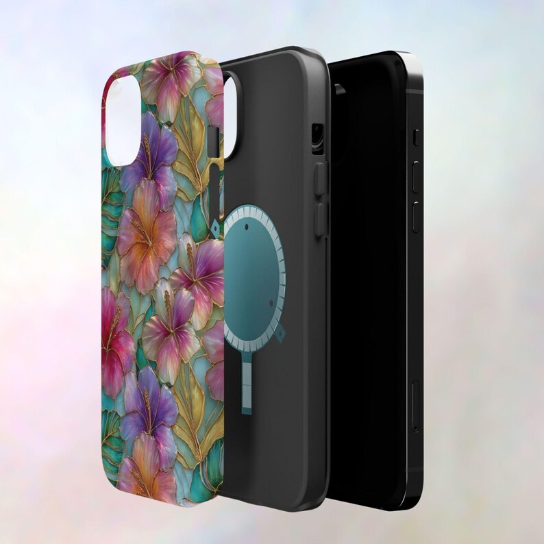 May include: Three phone cases shown in a layered arrangement. The front case features a vibrant floral pattern with pink, purple, and orange hibiscus flowers and gold-toned leaf outlines on a teal background. The middle case is black with a circular magnetic charging ring graphic. The back case is solid black.