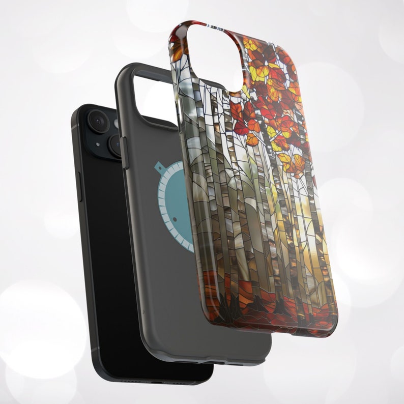 May include: Three phone cases. The first is black, the second is gray with a blue and white graphic, and the third features a stained-glass design of autumn trees with red, orange, and yellow leaves. The cases are designed to protect the phone.