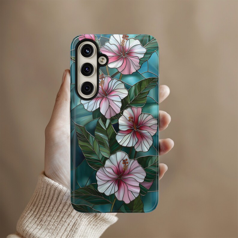 May include: A phone case with a stained glass design featuring pink and white hibiscus flowers on a teal background.