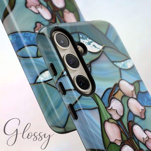 Pu&ograve; includere: Una custodia per telefono con un design in vetro colorato con fiori blu, rosa e verdi. La custodia ha una finitura lucida e un ritaglio per la fotocamera.