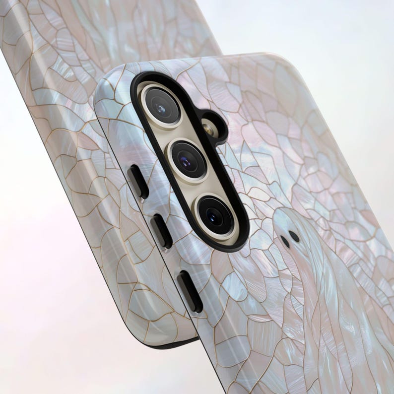 May include: A white phone case with a pearly, mosaic-like design. The case has a raised camera bump with three black lenses.