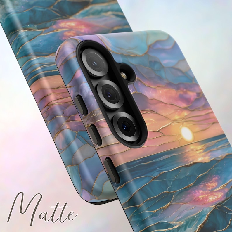 May include: A phone case with a sunset design. The case features a vibrant sunset over the ocean, with shades of blue, orange, and gold. The word "Matte" is written in cursive at the bottom of the image.