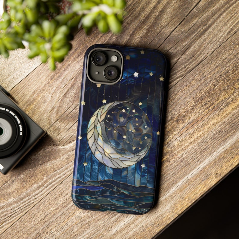 Puede incluir: Una funda de tel&eacute;fono azul y dorada con un dise&ntilde;o de luna creciente y estrellas. La luna est&aacute; hecha de un mosaico de azulejos de diferentes colores.