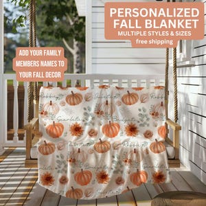 May include: A personalized fall blanket with a repeating pattern of orange pumpkins, flowers, and names. The blanket is displayed on a wooden swing on a porch. Text on the blanket reads "Robbie", "Juliette", "Scarlette", and "Bridgette".