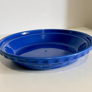 Peut inclure: Un plat à tarte rond et profond avec une finition émaillée bleu cobalt éclatante. Le bord extérieur présente un motif décoratif en vannerie moulée, tandis que la surface intérieure est lisse et brillante avec un point central légèrement creux.