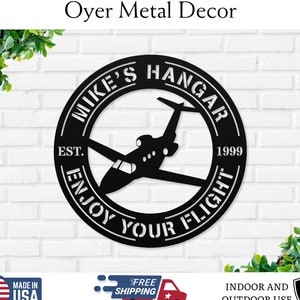 May include: Black metal sign with the text "Mike's Hangar Est. 1999 Enjoy Your Flight" and a silhouette of a private jet.