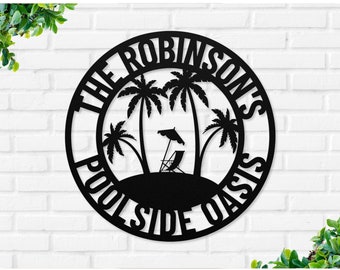 May include: Black metal sign with the text "The Robinsons Poolside Oasis" in a circle with palm trees and a lounge chair with an umbrella.