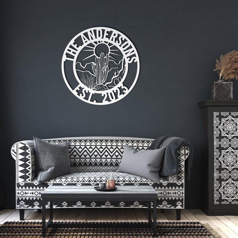 May include: White metal wall decor with a circular design featuring a cactus, sun, and mountains. The text "The Andersons Est. 2023" is displayed on the circle.