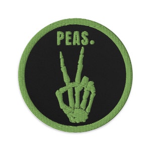 May include: Green embroidered patch with a black background. The patch features a skeleton hand making a peace sign and the text "PEAS."