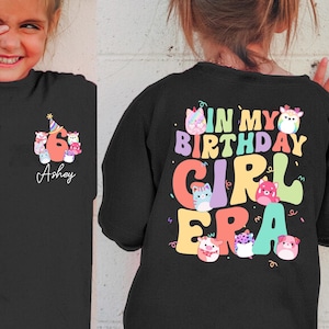 Puede incluir: Camiseta negra con un gráfico colorido en la parte posterior que dice "In My Birthday Girl Era" con un número 6 y un sombrero de cumpleaños en la parte delantera. La camiseta está personalizada con el nombre "Ashey".